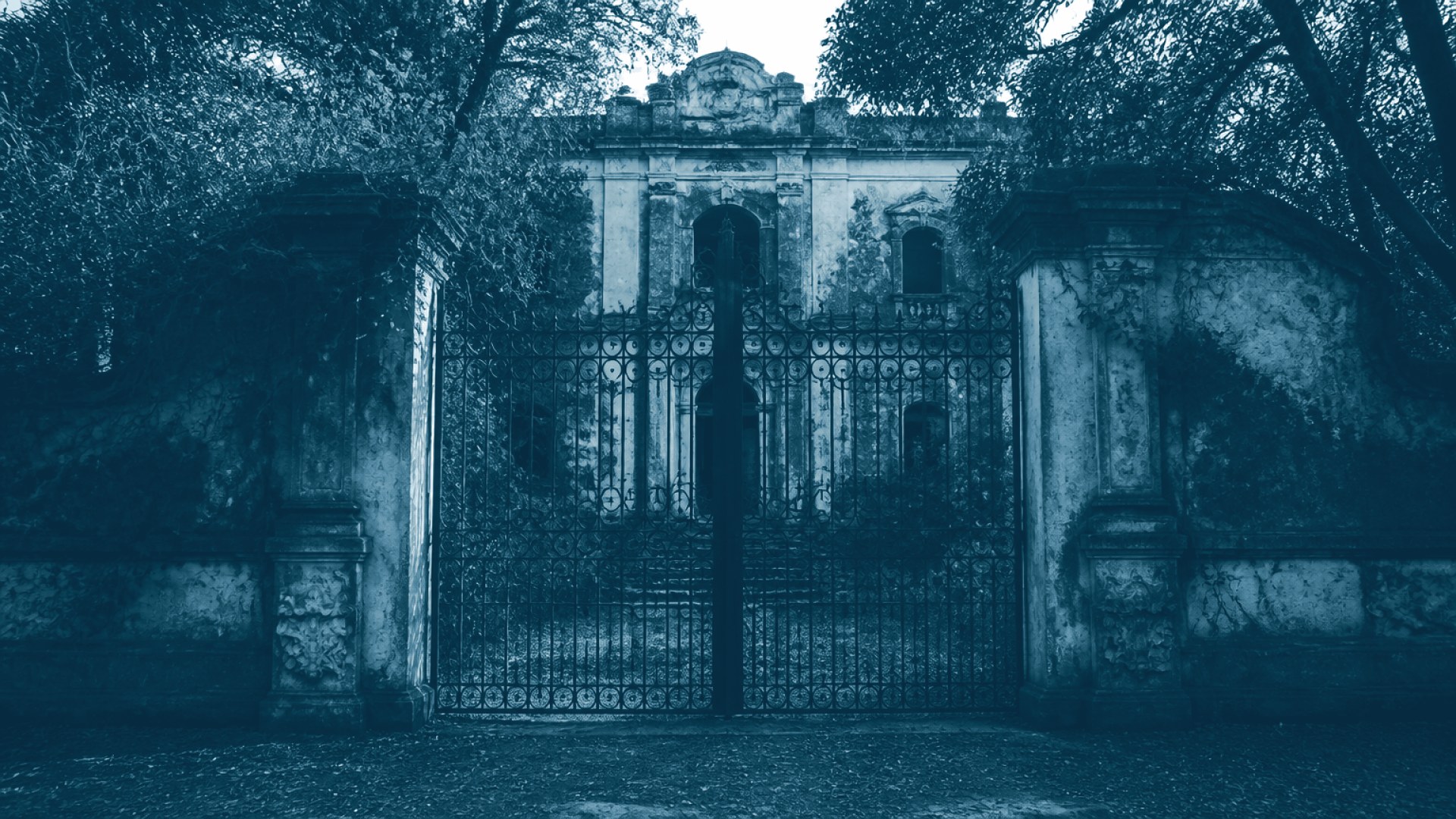 Portão de ferro fechado diante de prédio colonial em ruínas