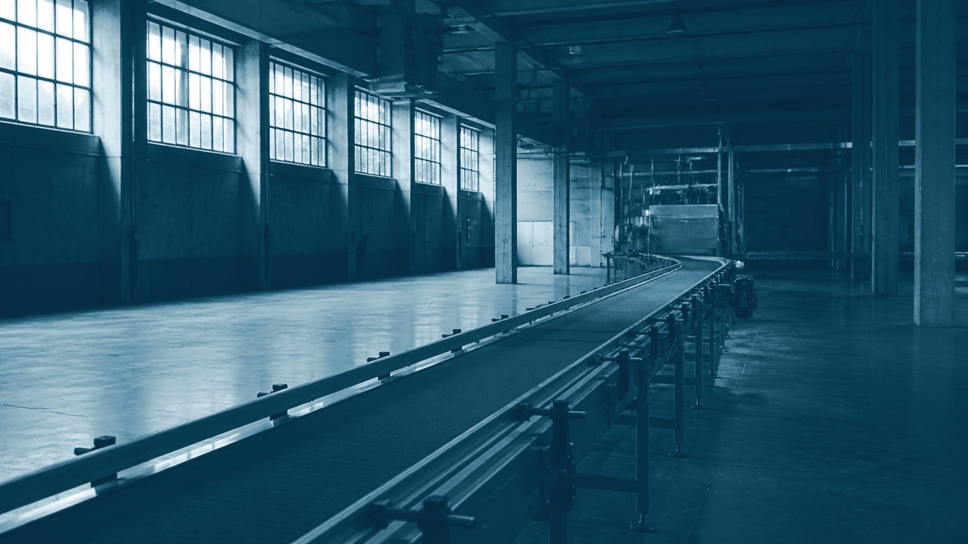 Chão de fábrica vazio com esteira parada sob luz industrial
