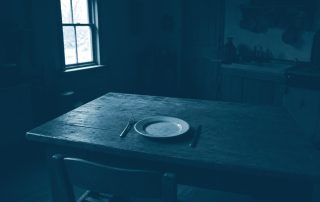 Mesa de jantar vazia com um prato solitário iluminado