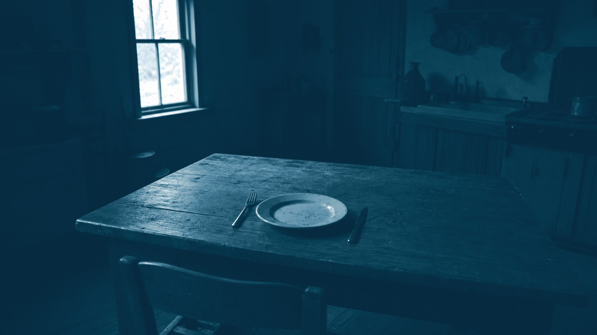 Mesa de jantar vazia com um prato solitário iluminado