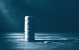 Pilha alta de moedas ao lado de uma única moeda