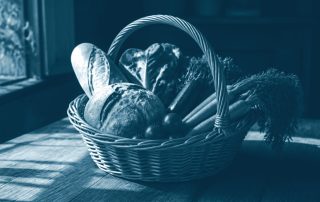 Cesta de vime com pão e vegetais sobre mesa