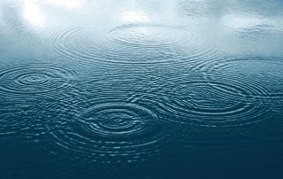 Ondulações se espalhando de vários pontos na superfície de um lago parado