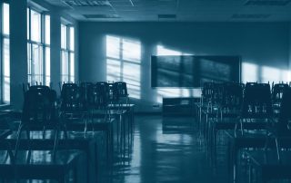 Sala de aula vazia com cadeiras empilhadas sobre mesas