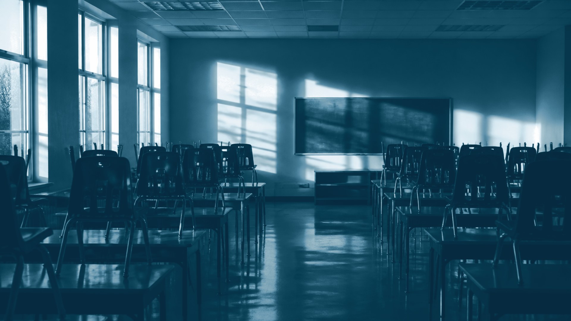 Sala de aula vazia com cadeiras empilhadas sobre mesas