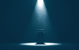 Holofote iluminando púlpito vazio em palco escuro e silencioso