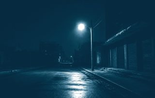 Poste de luz piscando em rua escura durante apagão
