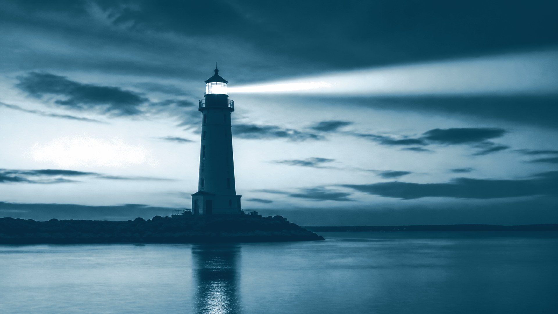 Farol aceso contra o céu ao entardecer, mar calmo
