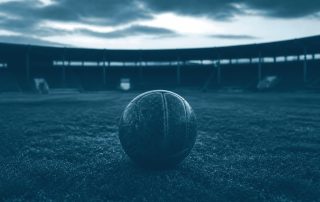 Bola de couro parada em campo de estádio vazio
