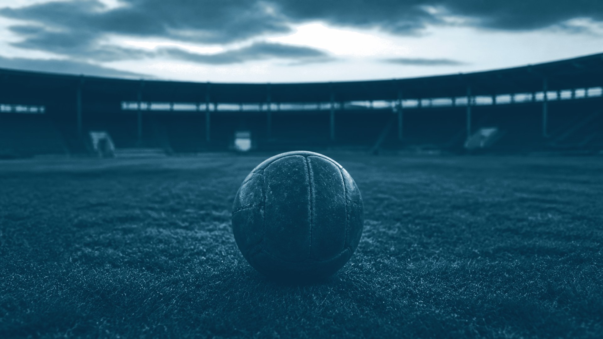 Bola de couro parada em campo de estádio vazio