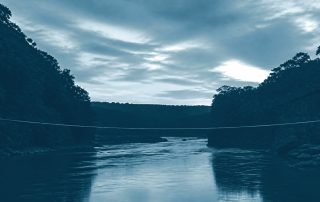 Corda bamba estendida sobre rio calmo ao entardecer