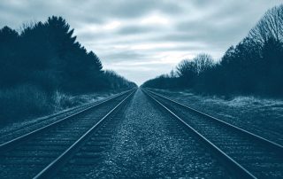 Trilhos de trem convergindo para um único ponto no horizonte