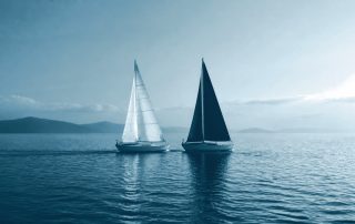 Dois pequenos barcos avançando lado a lado em velocidade igual