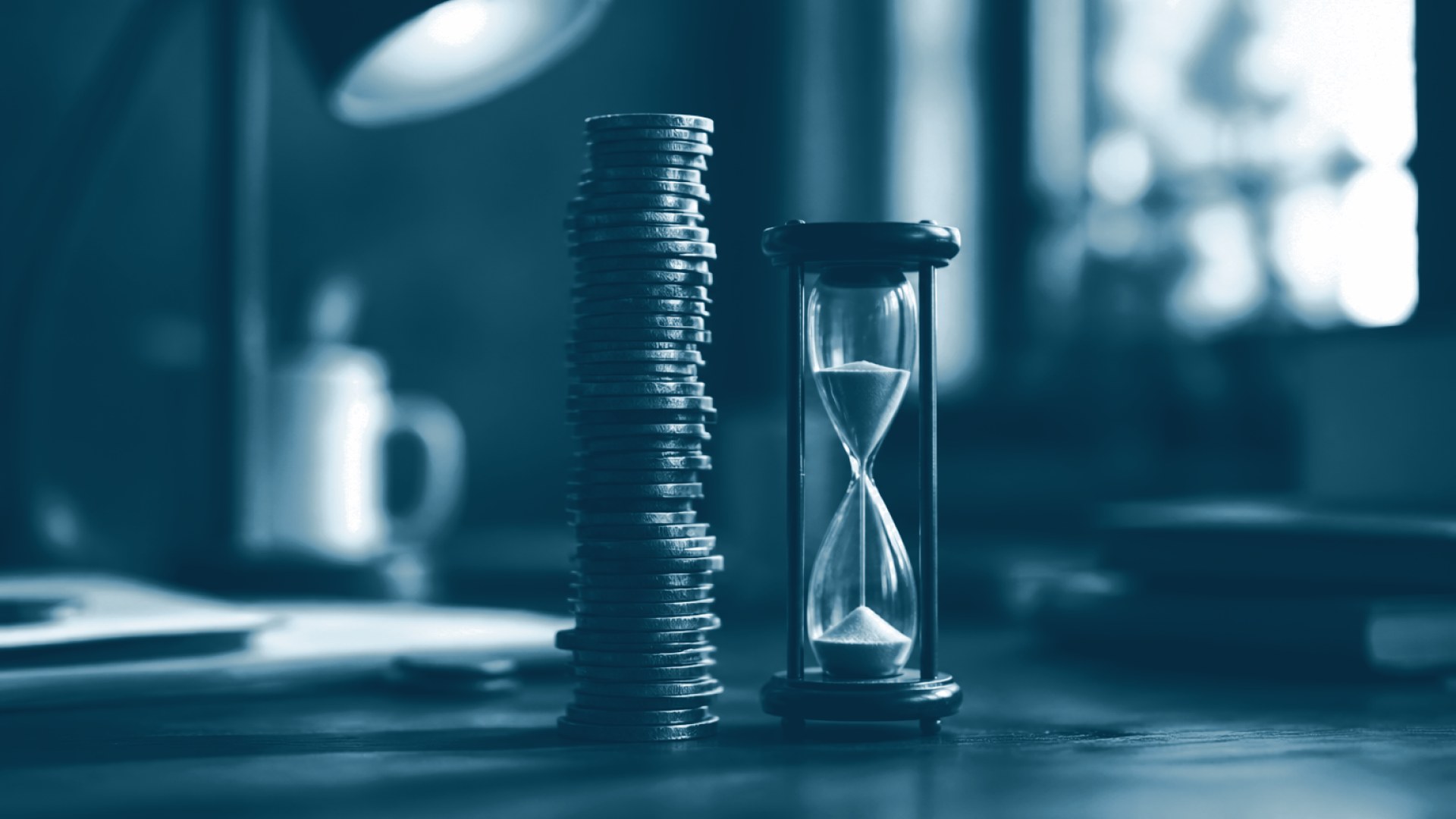 Pilha de moedas desgastadas ao lado de ampulheta