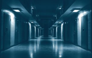 Corredor de presídio vazio com portas de cela fechadas