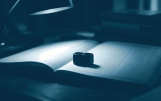 Par de dados pousado sobre livro-razão aberto na mesa