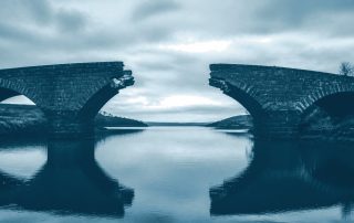 Ponte com um trecho faltando sobre águas calmas e paradas