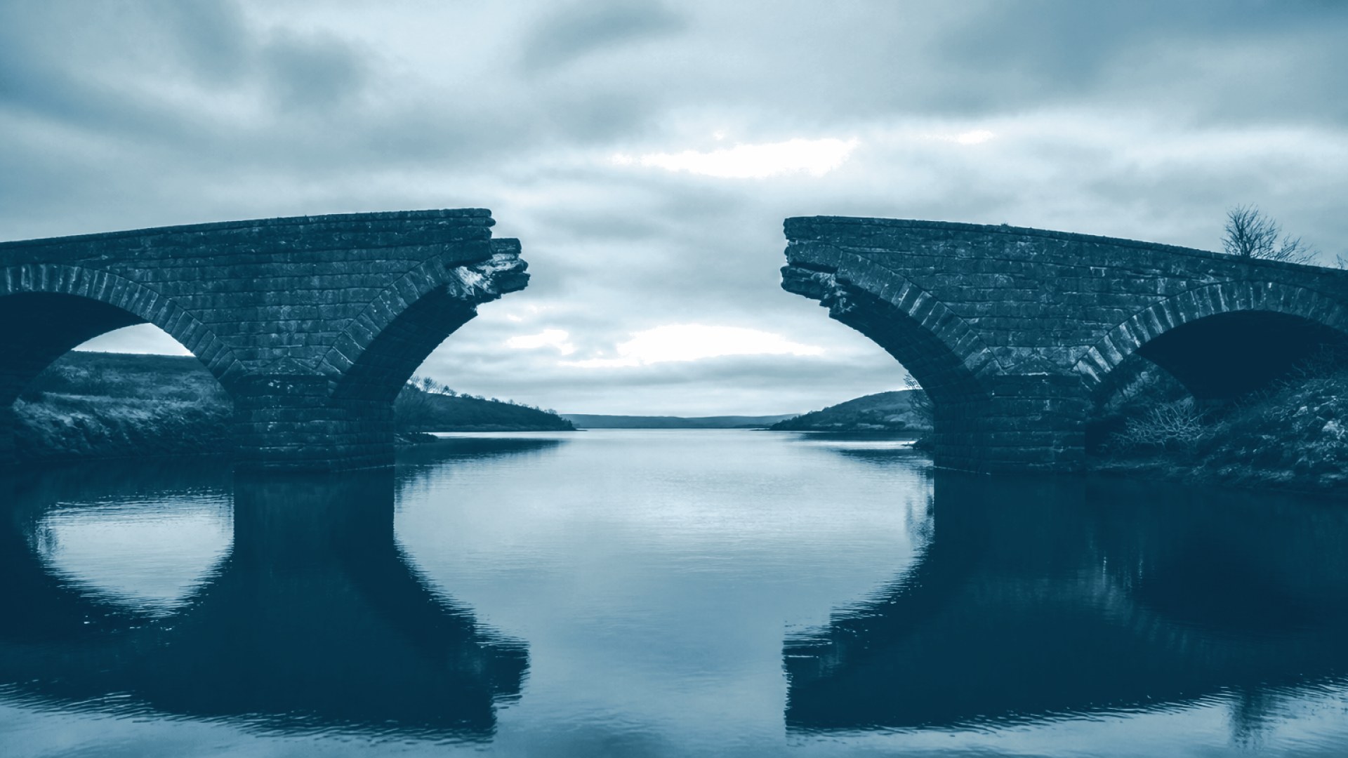 Ponte com um trecho faltando sobre águas calmas e paradas