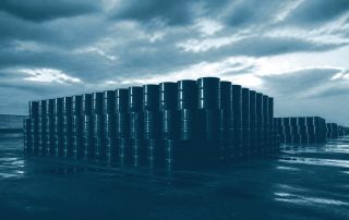 Fileiras de barris de petróleo empilhados em pátio industrial